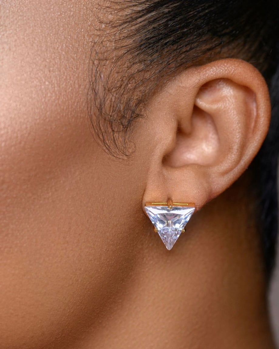 A pair of Earring Envy Pyramid Stud Earrings in 18k gold plating. Each stud features a high-clarity, triangular-cut 5A cubic zirconia stone with handset pavé detailing, creating a sharp, three-dimensional geometric silhouette.